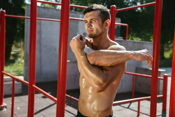 Giovane uomo muscoloso mentre fa il suo allenamento fuori al parco giochi — Foto Stock