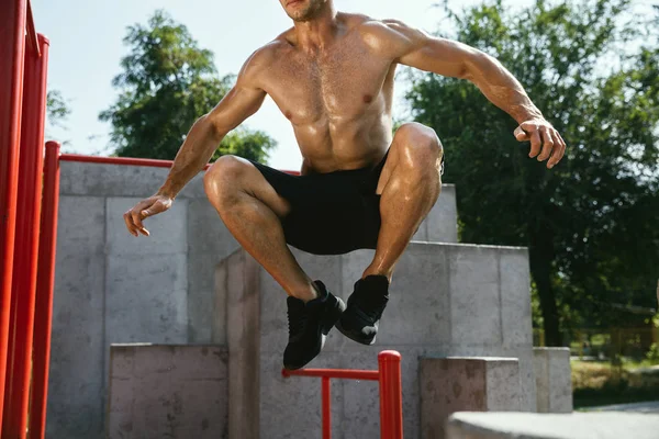 Joven hombre musculoso mientras hace su entrenamiento fuera en el patio de recreo — Foto de Stock