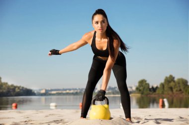 Genç sağlıklı kadın atlet plajda egzersiz yapıyor