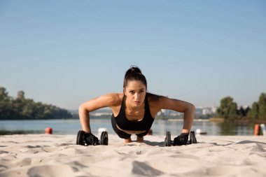 Genç sağlıklı kadın atlet plajda egzersiz yapıyor