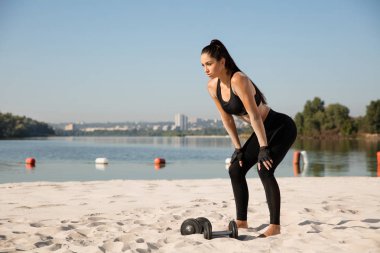 Genç sağlıklı kadın atlet plajda egzersiz yapıyor