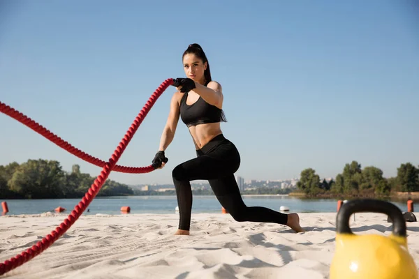 Jovem atleta feminina saudável fazendo exercício na praia — Fotografia de Stock