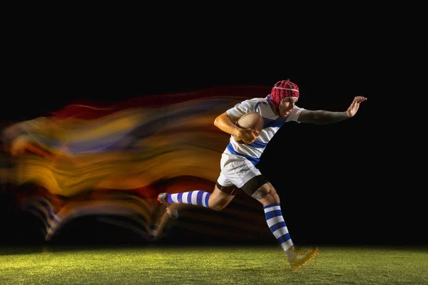 Ein kaukasischer Mann spielt Rugby im Stadion in gemischtem Licht — Stockfoto