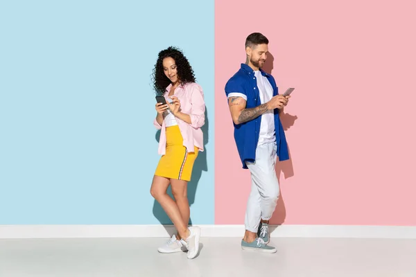 Young emotional man and woman on pink and blue background — Stock Photo, Image