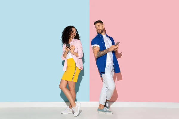 Young emotional man and woman on pink and blue background — Stock Photo, Image