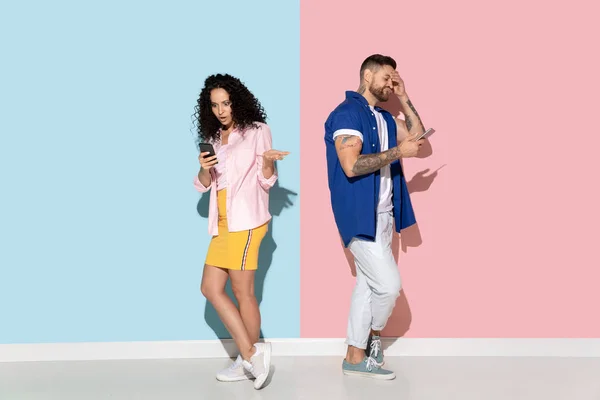 Mladý emocionální muž a žena na růžovém a modrém pozadí — Stock fotografie