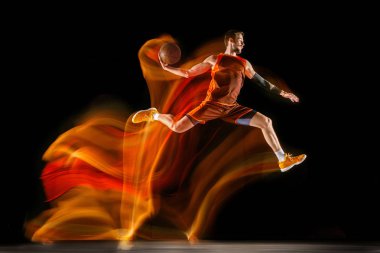 Karışık ışıkta karanlık arka plana karşı genç kafkas basketbolcu