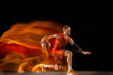 Karışık ışıkta karanlık arka plana karşı genç kafkas basketbolcu