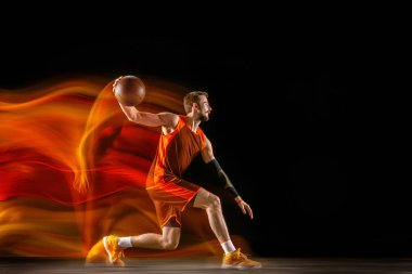Karışık ışıkta karanlık arka plana karşı genç kafkas basketbolcu