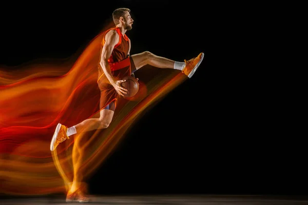 Unga kaukasiska basketspelare mot mörk bakgrund i blandat ljus — Stockfoto