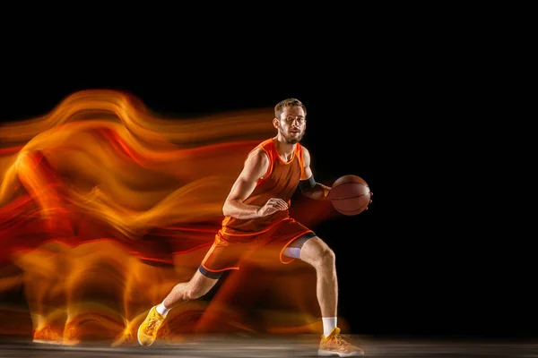 Jonge blanke basketballer tegen donkere achtergrond in gemengd licht — Stockfoto