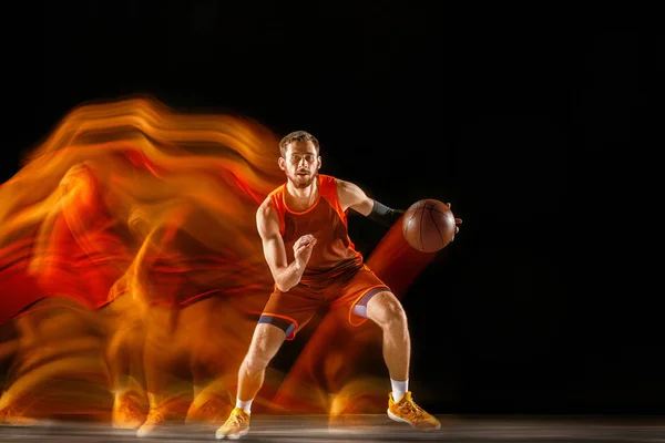 Junge kaukasische Basketballerin vor dunklem Hintergrund in gemischtem Licht — Stockfoto