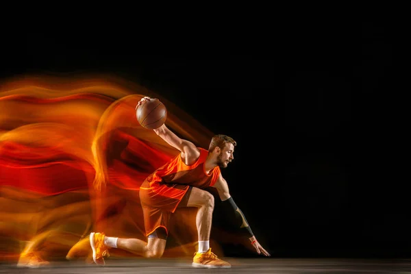 Joven jugador de baloncesto caucásico contra fondo oscuro en luz mixta —  Fotos de Stock