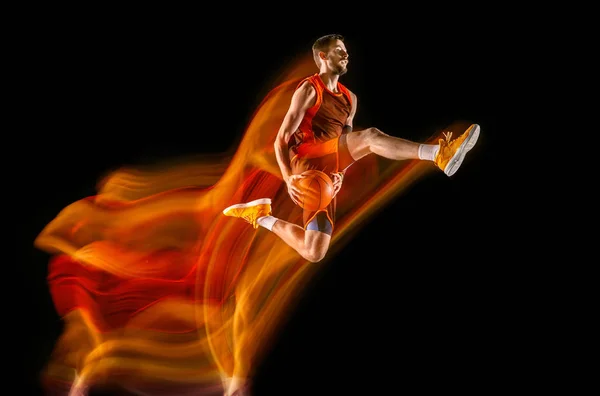 Joven jugador de baloncesto caucásico contra fondo oscuro en luz mixta — Foto de Stock