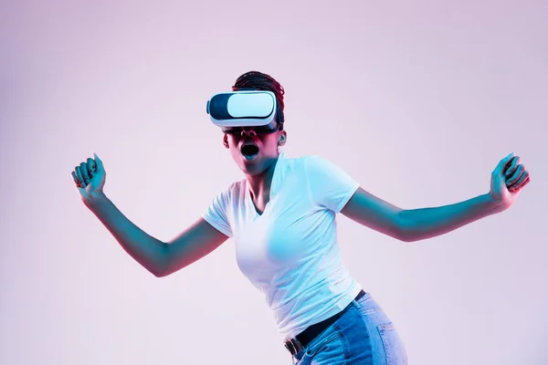 Young african-american womans using VR-glasses in neon light