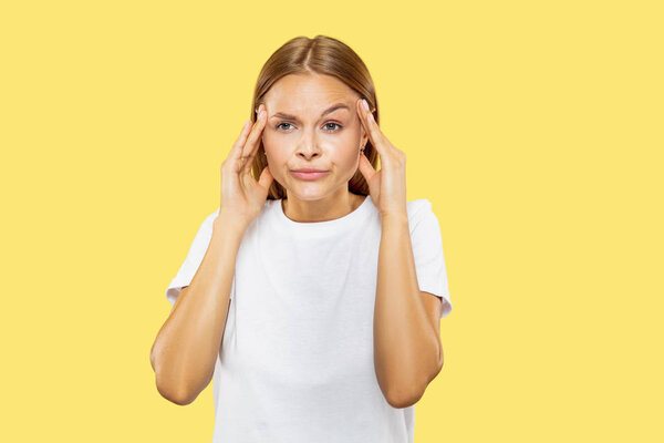 Caucasian young womans half-length portrait on yellow background
