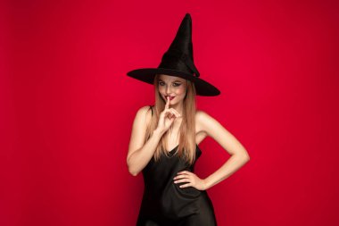 Kırmızı arka plan üzerinde bir cadı olarak şapka genç kadın