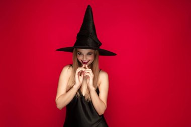 Kırmızı arka plan üzerinde bir cadı olarak şapka genç kadın