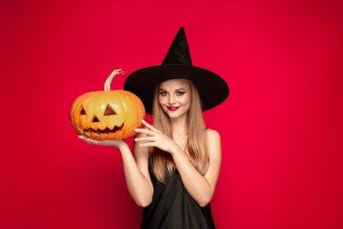 Kırmızı arka plan üzerinde bir cadı olarak şapka genç kadın