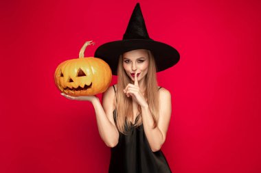 Kırmızı arka plan üzerinde bir cadı olarak şapka genç kadın