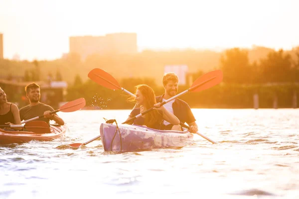 Heureux amis kayak sur la rivière avec coucher de soleil sur le fond — Photo