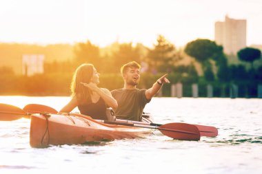 Kendinden emin genç çift arka planda gün batımı ile birlikte nehir üzerinde kayak