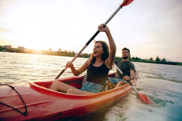 Fiduciosa giovane coppia kayak sul fiume insieme con il tramonto sullo sfondo — Foto Stock