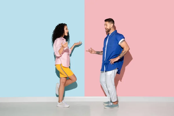 Młody emocjonalny mężczyzna i kobieta na różowym i niebieskim tle — Zdjęcie stockowe