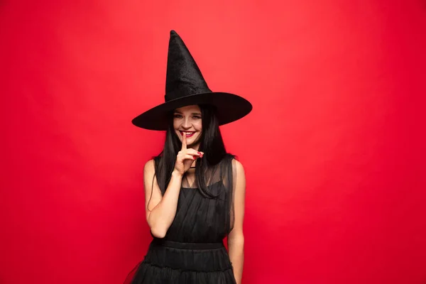 Fiatal nő kalapot és ruhát, mint egy boszorkány a vörös háttér — Stock Fotó