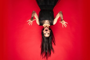 Şapkalı genç kadın ve kırmızı arka planda bir cadı gibi elbise