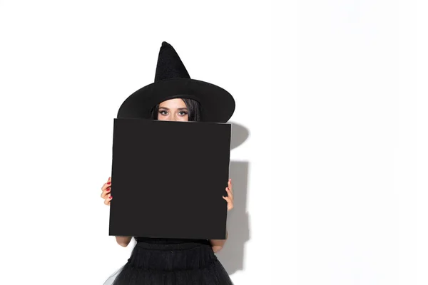 Mladá žena v klobouku a oblékat se jako čarodějka na bílém pozadí — Stock fotografie