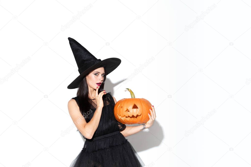 Young woman in hat and dress as a witch on white background