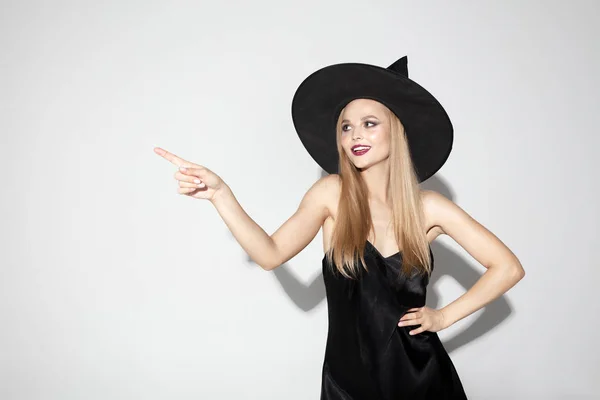 Mujer joven con sombrero como bruja sobre fondo blanco — Foto de Stock