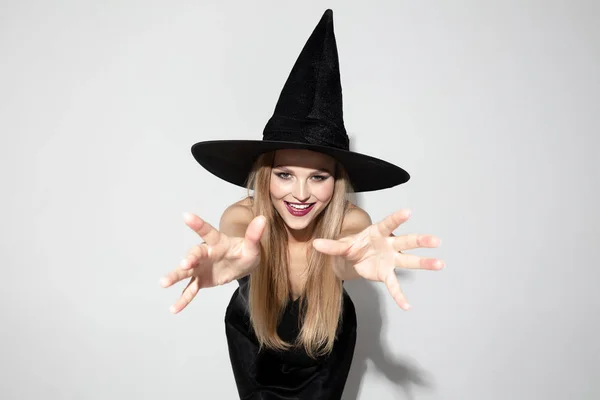 Молодая женщина в шляпе как ведьма на белом фоне — стоковое фото