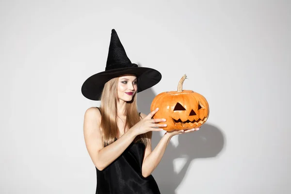 Mladá žena v klobouku jako čarodějka na bílém pozadí — Stock fotografie
