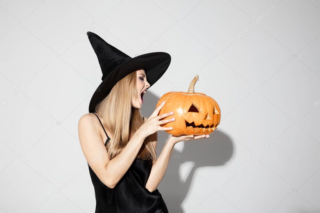 Young woman in hat as a witch on white background