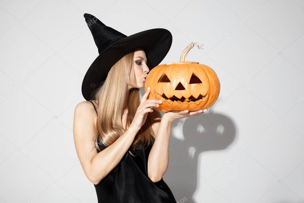 Young woman in hat as a witch on white background
