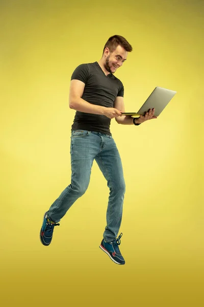 Retrato de comprimento total de homem de salto feliz com gadgets no fundo amarelo — Fotografia de Stock