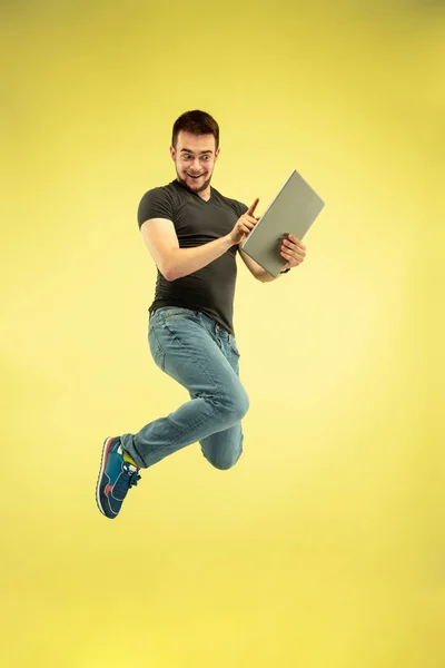 Retrato de comprimento total de homem de salto feliz com gadgets no fundo amarelo — Fotografia de Stock