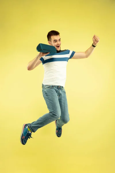 Retrato de comprimento total de homem de salto feliz com gadgets no fundo amarelo — Fotografia de Stock