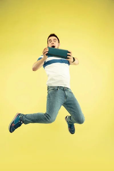 Volledige lengte portret van Happy Jumping man met gadgets op gele achtergrond — Stockfoto