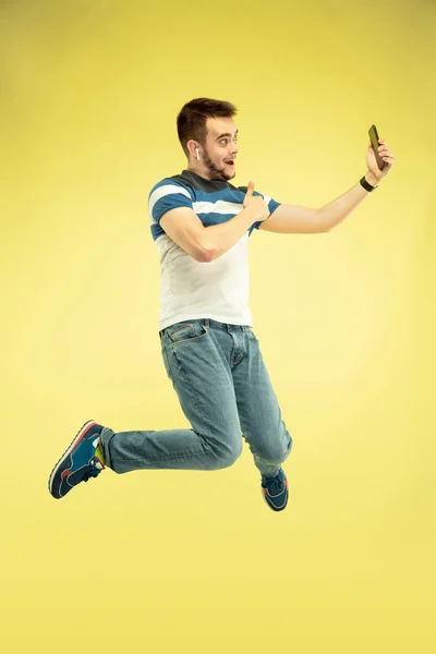 노란색 배경에 가젯행복 점프 남자의 전체 길이 초상화 — 스톡 사진
