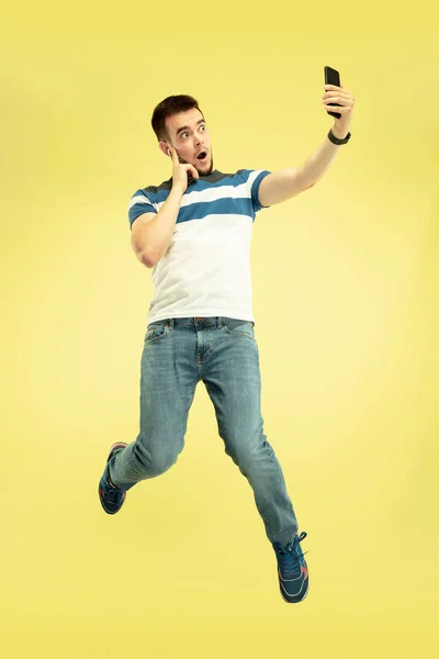 Ganzkörperporträt eines glücklichen springenden Mannes mit Gadgets auf gelbem Hintergrund — Stockfoto