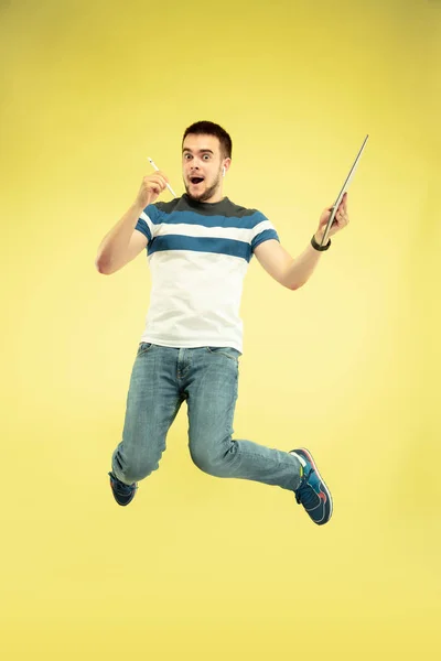 Volledige lengte portret van Happy Jumping man met gadgets op gele achtergrond — Stockfoto