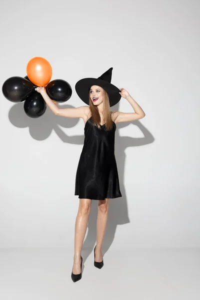 Mladá žena v klobouku jako čarodějka na bílém pozadí — Stock fotografie