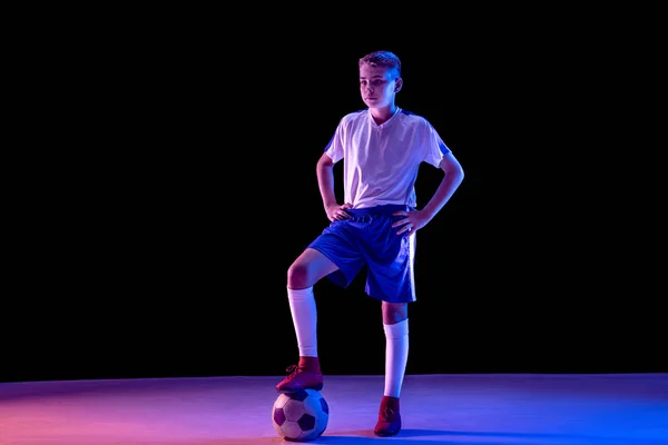 Молодий хлопчик як футболіст або футболіст на темному фоні студії — стокове фото