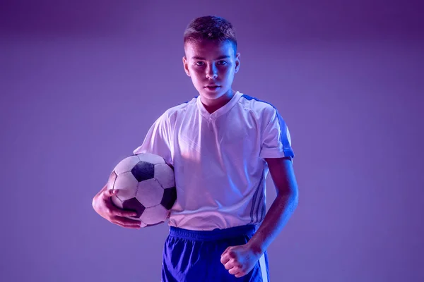 Young boy as a soccer or football player on dark studio background