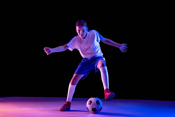 Young boy as a soccer or football player on dark studio background