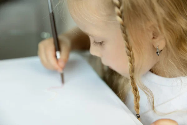Девочка учится писать или рисовать. Концепция домашнего обучения — стоковое фото