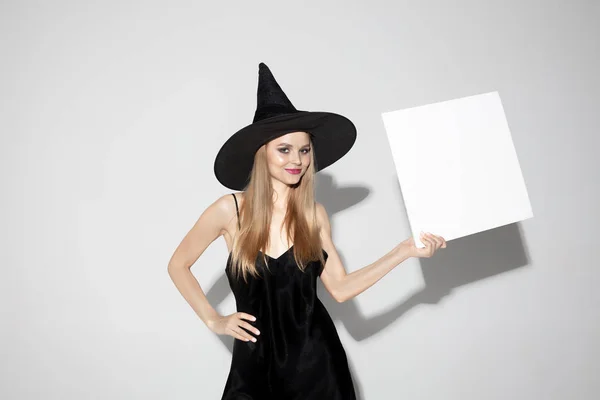 Молодая женщина в шляпе как ведьма на белом фоне — стоковое фото